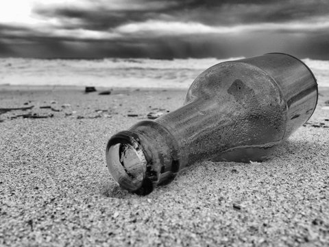 Close-up Of Bottle At Beach Against Sky