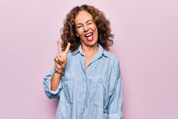 Middle age beautiful woman wearing casual denim shirt standing over pink background smiling with...