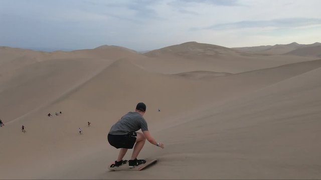 Young man sandboards in the Peruvian dessert