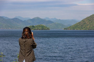 Fototapeta na wymiar Asian woman tourist take a photo landscape of mountain and blue sky