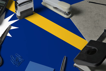 Nauru flag with office clerk workplace background. National stationary concept with office tools.