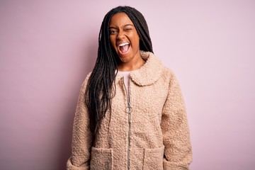 Young african american woman wearing fashion winter coat over pink isolated background winking looking at the camera with sexy expression, cheerful and happy face.