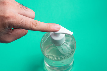 Man hand in container with alcohol gel on the light blue background