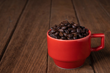 
Coffee beans in a red mug on a wooden table