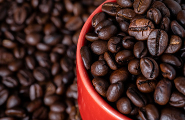 
Coffee beans in a red mug on a wooden table