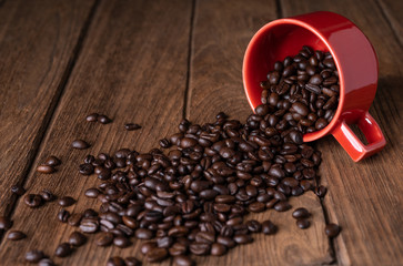 
Coffee beans in a red mug on a wooden table