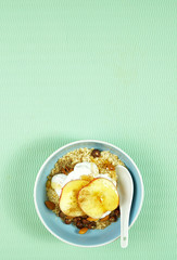 Healthy breakfast bowl with oats, spices, yogurt, fresh fruit, nuts, honey and high fiber LSA on modern green background. Top view flatlay with negative copy space. Vertical.
