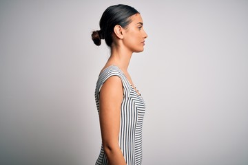 Young beautiful brunette woman wearing casual striped dress over isolated white background looking to side, relax profile pose with natural face with confident smile.