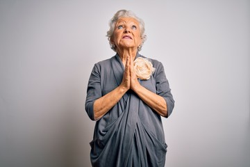 Senior beautiful grey-haired woman wearing casual dress standing over white background begging and praying with hands together with hope expression on face very emotional and worried. Begging.