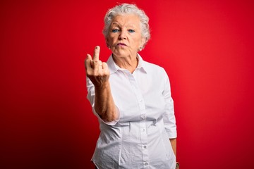 Senior beautiful woman wearing elegant shirt standing over isolated red background Showing middle finger, impolite and rude fuck off expression