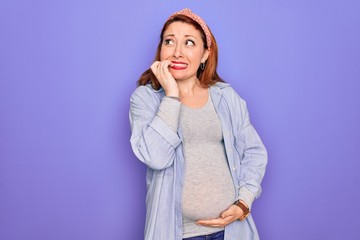 Young beautiful redhead pregnant woman expecting baby over isolated purple background looking stressed and nervous with hands on mouth biting nails. Anxiety problem.