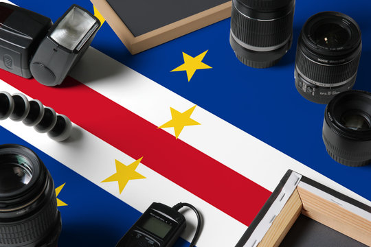 Cape Verde national flag with top view of personal photographer equipment and tools on white wooden table, copy space.