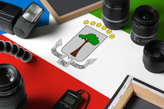 Equatorial Guinea national flag with top view of personal photographer equipment and tools on white wooden table, copy space. - Powered by Adobe