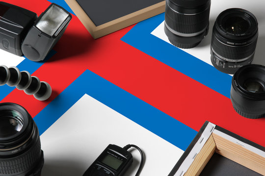 Faroe Islands national flag with top view of personal photographer equipment and tools on white wooden table, copy space.