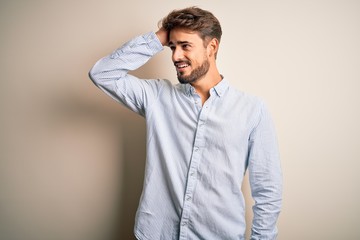 Young handsome man with beard wearing striped shirt standing over white background smiling...