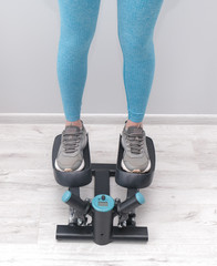 Feet of woman exercising on a twister  stepper. Digital display, keeping fit at home.