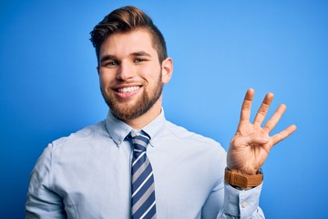 Young blond businessman with beard and blue eyes wearing elegant shirt and tie standing showing and pointing up with fingers number four while smiling confident and happy.