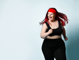 Close up portrait of young attractive plus-size model with flowing red hair, squinted eyes and...