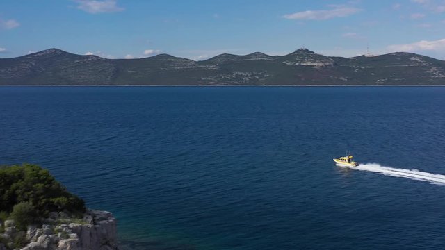 Speedboat from Coast Guard cruising near beautiful Island in Adriatic Sea - Aerial Drone View