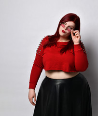 Overweight redhead woman in red spiked top, black skirt. She lowered her sunglasses and looking at...