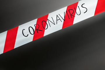 Label coronavirus. Red and white warning tape with the inscription coronavirus close up on black...