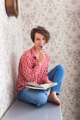 Girl sitting on chest of drawers at home.