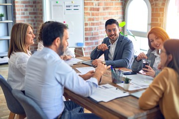 Group of business workers working together. Sitting on desk speaking at the office