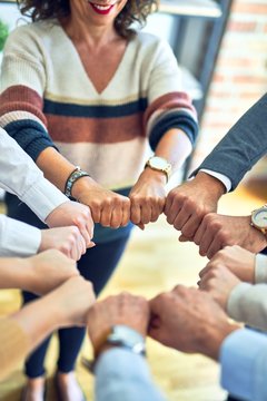 Group of business workers standing bumping fists at the office