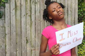 Sad Girl outdoors hold I Miss Dance Class homemade sign wearing pink leotard