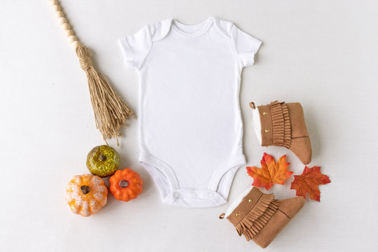 Plain white baby bodysuit vest mockup surrounded by autumn/fall baby props - baby clothing mockup