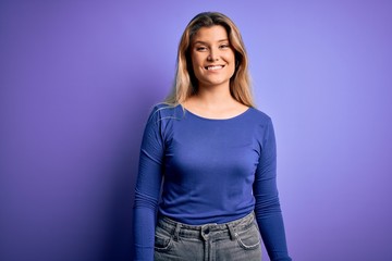 Young beautiful blonde woman wearing casual t-shirt over isolated purple background with a happy and cool smile on face. Lucky person.