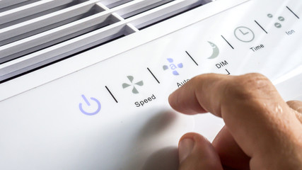 Close up of hand turning ON air filter. Portable air purifier for allergies.