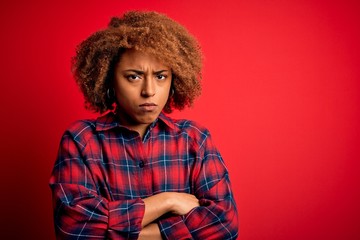 Fototapeta na wymiar Young beautiful African American afro woman with curly hair wearing casual shirt skeptic and nervous, disapproving expression on face with crossed arms. Negative person.