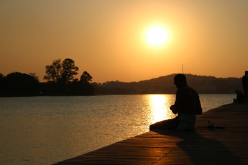 silhouette of a man sitting on a pier at sunset
