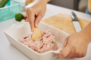 Close-up image of woman mixing ground meat with cut leek and species with wooden spatula in ceramic cooking tray