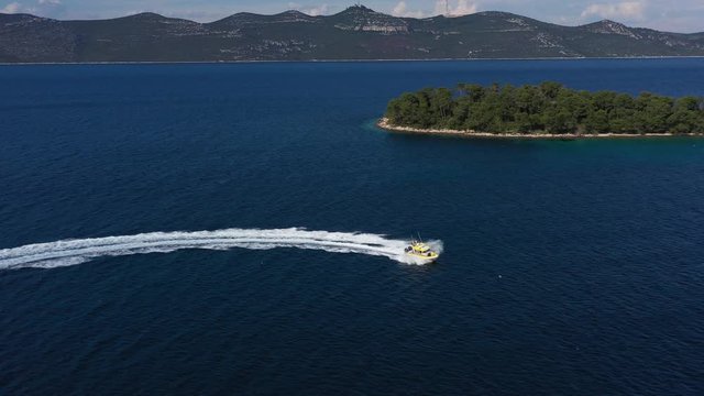 Speedboat from Coast Guard cruising near beautiful Island in Adriatic Sea - Aerial Drone View