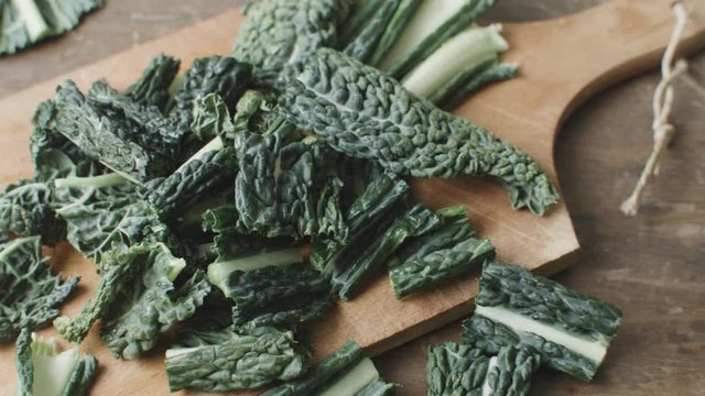 A hand covers and discover the camera with a piece of kale