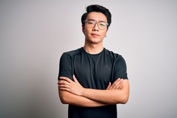 Young handsome chinese man wearing black t-shirt and glasses over white background skeptic and...
