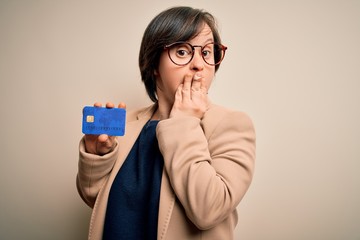 Young down syndrome business woman holding credit card as customer payment cover mouth with hand...