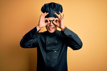 Young brazilian chef man wearing cooker uniform and hat over isolated yellow background doing ok...
