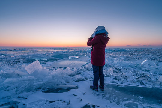 A traveller standing on ice in Baikal frozen lake in winter season at sunrise, Uzury bay, Siberia, Russia