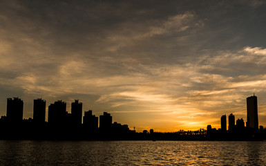Fototapeta na wymiar Silhouette Buildings By Calm Sea At Sunset