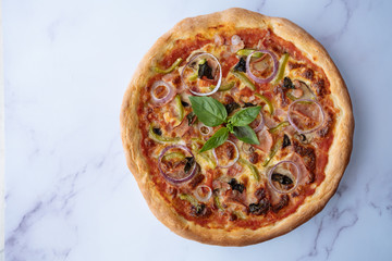 Homemade pizza with basil, mushrooms, onion rings, ham and pepper. Artisan pizza top view