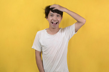 portrait of Asian man wearing a white shirt with a cheerful and attractive expression isolated on a yellow background
