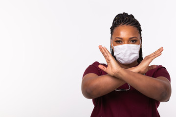 Doctor crossed hands on chest on white background with copy space. He is wearing medical mask. No or stop gesture. Coronavirus, covid-19 and pandemic concept.
