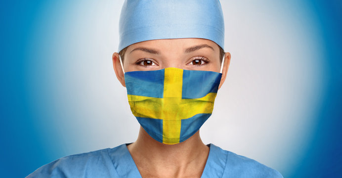 Sweden COVID-19 doctor woman wearing face mask with swedish flag print for coronavirus hope. Asian nurse portrait on blue background.