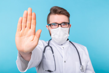 Doctor man using mask with open hand doing stop sign with serious and confident expression, defense gesture. Coronavirus outbreak, covid-19 and pandemic concept. Close-up.