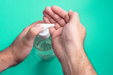 Man hand in container with alcohol gel on the light blue background