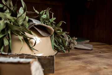 Interior details Finnish sauna steam room or Russian bathhouse with traditional sauna accessories: basin, birch broom, felt hat, birch wood medicinal herbs . Relax concept. Copy space