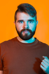 Neon light studio portrait of attractive male model with mustaches and beard wears t-shirt.